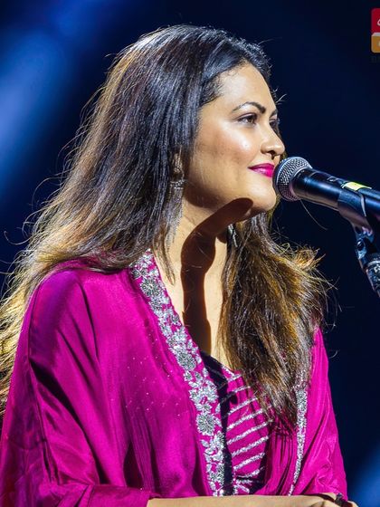 A close-up profile of Priyanka Barve on stage, showcasing her flawless makeup and the silver embroidery on her outfit.