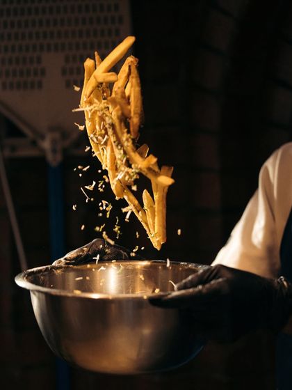 Our cheesy fries being tossed with parmesan and herbs. It's a simple side dish done right, perfect for sharing.