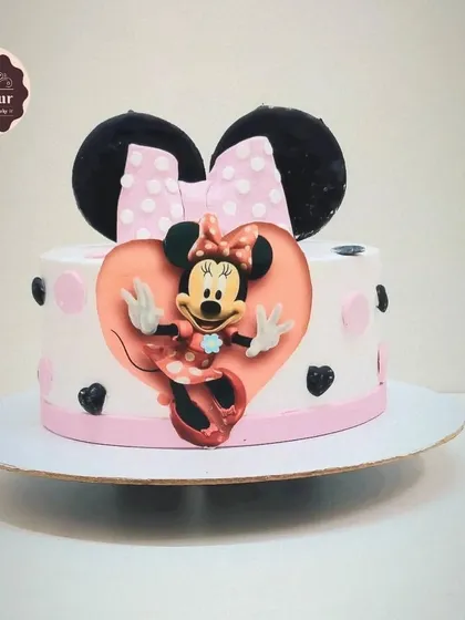 A cute Minnie Mouse theme cake. This 1 kg chocolate truffle cake features Minnie in a heart frame with her iconic bow, a sweet and simple design for any fan.