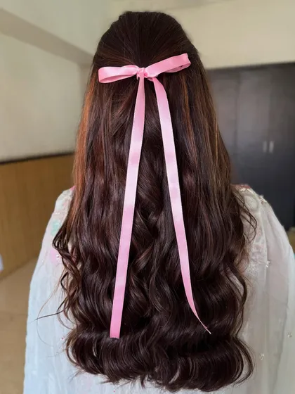 A simple yet chic hairstyle featuring soft waves and a cute pink ribbon. This look is perfect for a fun, carnival-themed event.