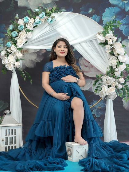A regal portrait of the mom-to-be, seated like a queen on her throne. The crown and the magnificent blue gown complete this majestic look.