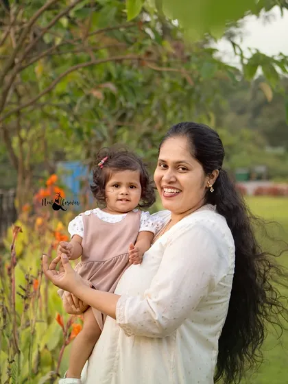 A lovely outdoor portrait of a mother and her daughter. The natural light and green surroundings create a soft and beautiful atmosphere for this tender moment.