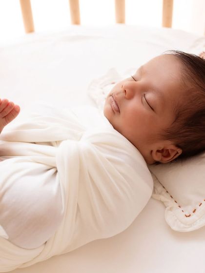 Another beautiful angle of the baby sleeping in their crib. The soft, natural light from the window creates a serene and timeless portrait.