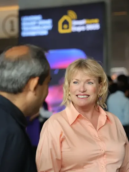 An international visitor engages in a friendly conversation near a pavilion entrance. Our event fosters a global community of smart home enthusiasts and professionals.