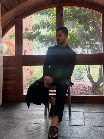 A moment of quiet reflection during a shoot for men's ethnic wear. The silhouette of the bandhgala against the arched window creates a powerful, regal image.
