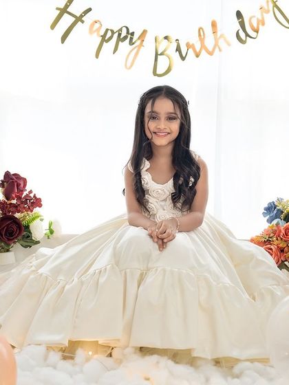 A full view of the dreamy birthday setup, with the girl sitting on a cloud-like floor surrounded by pastel balloons.