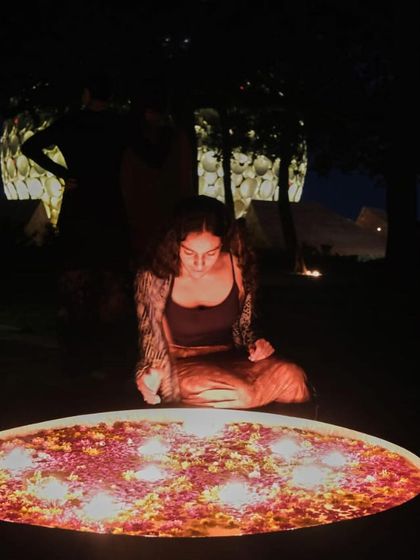 A contemplative moment by a bowl of floating candles at night. This serene image reflects the process of journaling and embracing the rawness and truth of our experiences.