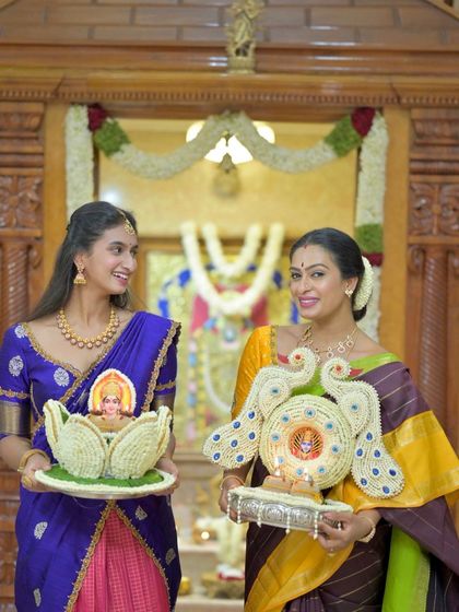 A shared smile between mother and daughter during a pooja, both looking radiant in their respective silk sarees.
