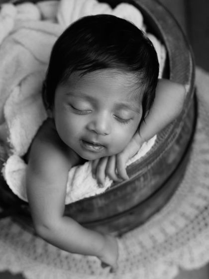 Another angle of a two-month-old baby in a bucket, this time in black and white. The classic style emphasizes the pose, the angle, and that adorable little smirk.