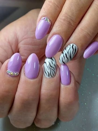 A chic combination of lavender polish, zebra print accent nails, and delicate rhinestone details at the cuticle.
