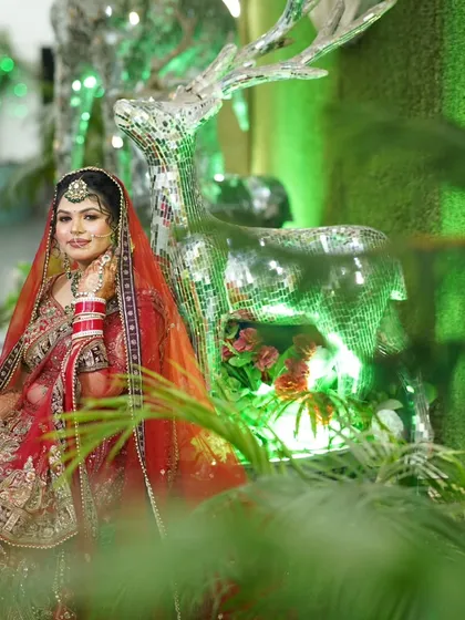A creative portrait of the bride next to a mirrored deer statue. The green lighting and unique prop make this a memorable shot.