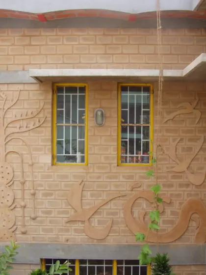 Building elements become a canvas for art. Here, relief patterns made from earth are integrated directly onto the exterior brick wall, turning a simple surface into a piece of art that tells a story.
