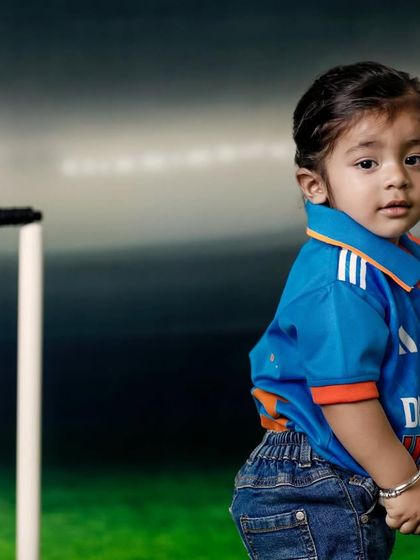 A future cricketer in the making, wearing the iconic blue jersey and ready to play. The stadium backdrop adds a professional touch to this fun, sporty photoshoot.