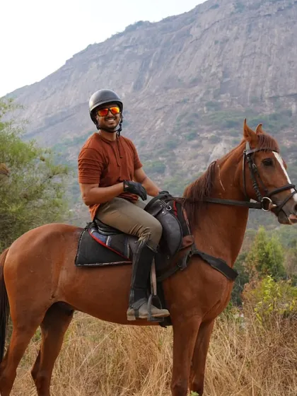 A happy rider on his handsome brown horse, pausing to enjoy the view during a safari ride through the hills.