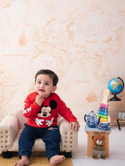 A classic character comes to life. This little boy looks adorable in his Mickey Mouse sweater in our travel-themed setup.