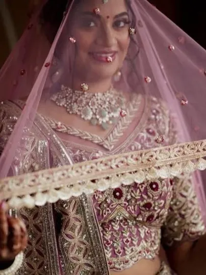 A beautiful shot of the bride under her veil. The makeup is designed to look soft and ethereal, even under the delicate fabric of the dupatta.