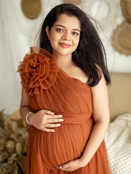 A beautiful solo portrait of the mom-to-be in a stunning rust-colored tulle gown. Her gentle smile and the soft, flowing fabric create a truly graceful image.