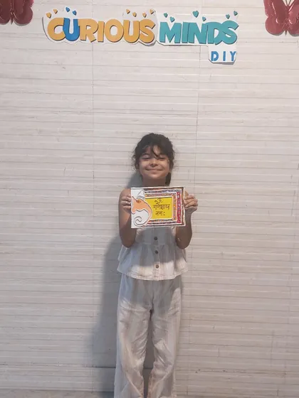 A proud student displays her Ganesha-themed Lippan art. We offer different art forms during our festive workshops, allowing children to explore various traditional and contemporary techniques.