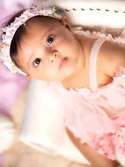A delicate and soft portrait from a unicorn-themed session. The pastel pink outfit and floral headband perfectly match the dreamy, magical atmosphere.