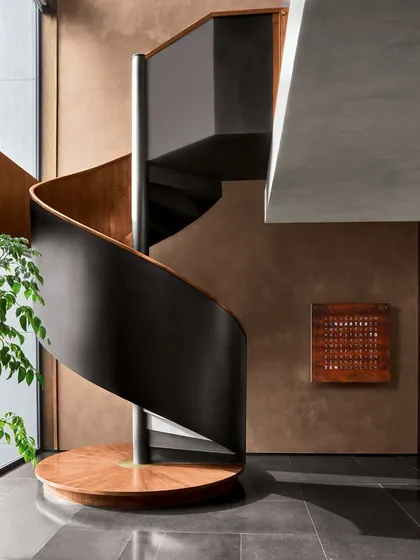 We believe staircases should be sculptural moments within a home. This spiral staircase at the Urban Hearth residence is crafted from matte black metal and polished wood, rising through a double-height void. Its form is a precise geometric statement that feels both modern and intuitive, anchoring the space while allowing light and air to flow freely.