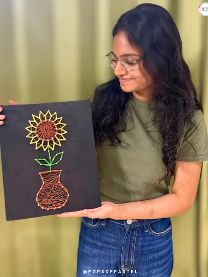 A beautiful finished piece. This participant admires her completed sunflower in a vase string art, a testament to her patience and creativity.