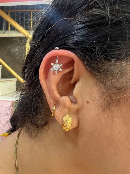 A beautiful snowflake hanging from the helix, paired with a simple gold hoop. This piece is perfect for adding a touch of winter magic to your look.