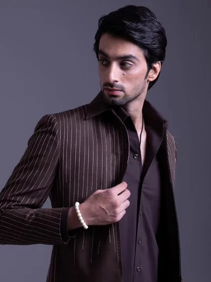 A brown pinstripe jacket worn open over a matching brown shirt. This look redefines traditional wear with a modern, relaxed sensibility.