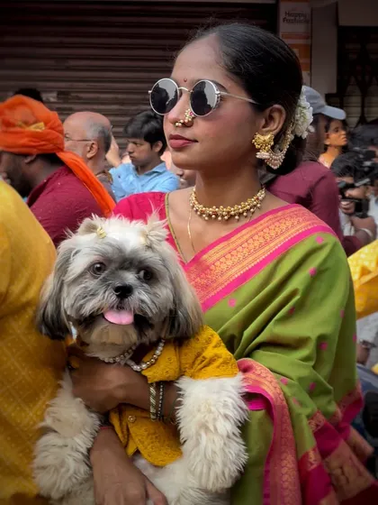 A modern Mumbaikar blending tradition with style, holding her dressed-up pet. This photo shows the evolving and inclusive nature of our cultural celebrations.
