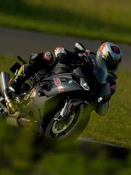 A BMW S1000RR captured mid-corner, framed by the lush green surroundings of the Madras International Circuit.