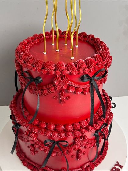 A full view of the dramatic two-tiered red "Scorpio Baby" cake, complete with elegant, long gold candles.