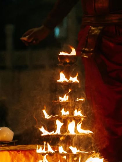A priest tends to a multi-tiered arrangement of diyas during the Aarti. This shot highlights the intricate preparations and the beauty of the ritual.