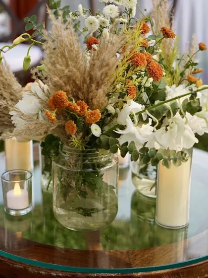 A close-up of a rustic centerpiece with pampas grass and wildflowers, perfect for a beachside boho theme.