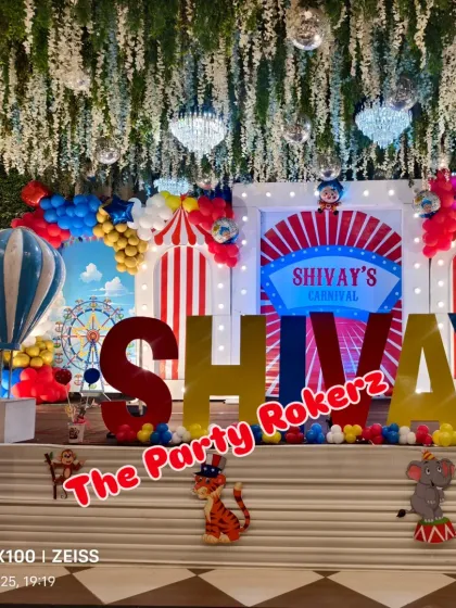 The main stage for a grand Carnival-themed first birthday. The setup includes a large backdrop, marquee letters, and numerous themed props like a Ferris wheel and circus animals.