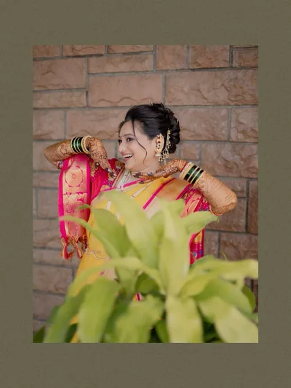 A candid shot of the bride laughing, partially obscured by a plant, which adds a natural and artistic element to the portrait.