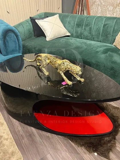 A sculptural coffee table with a black top and a striking red-accented base. The unique, asymmetric design makes it a piece of functional art for a modern living room.