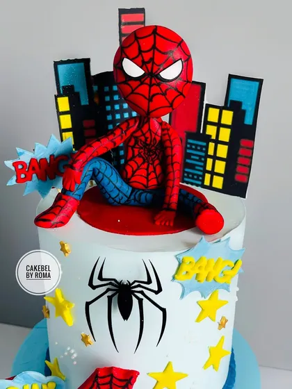 A detailed look at the hand-sculpted fondant Spider-Man topper, sitting thoughtfully atop the city he protects.