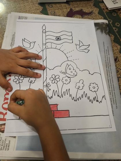 A student carefully coloring an Independence Day themed drawing, staying within the lines of the flag and flowers.