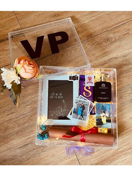 A personalized acrylic box hamper for a special occasion. This one was customized with initials and filled with a photo frame, a sentimental scroll, and polaroid pictures.