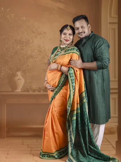 A full-length portrait showcasing the elegance of the traditional saree and kurta. The couple looks directly at the camera, sharing their joy with a confident smile.
