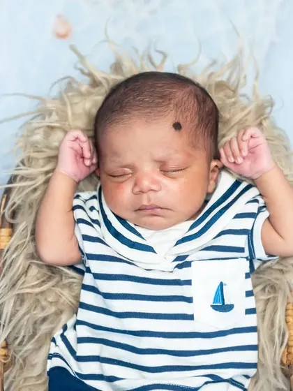 A top-down view of a sleeping newborn dressed in a cute sailor-themed outfit.