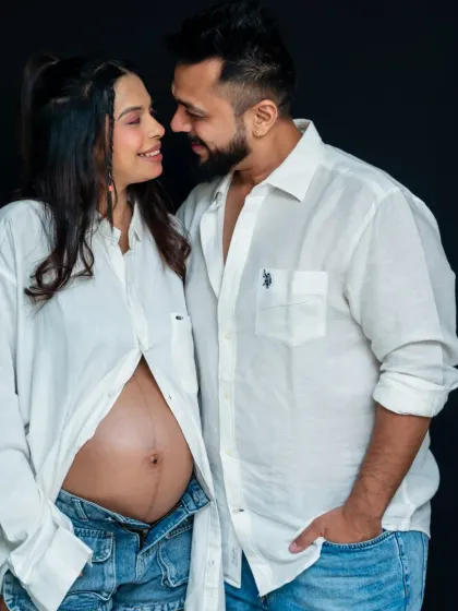 A beautiful, relaxed studio portrait of a couple. Their matching white shirts and the mom-to-be's bare bump create a natural and intimate feel.