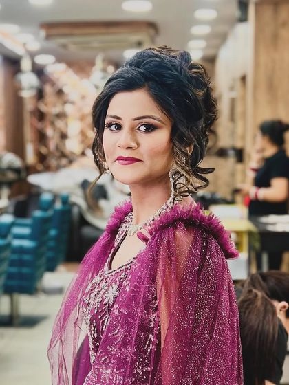 A close-up portrait of the client, highlighting the beautiful makeup and the intricate details of her curly updo.