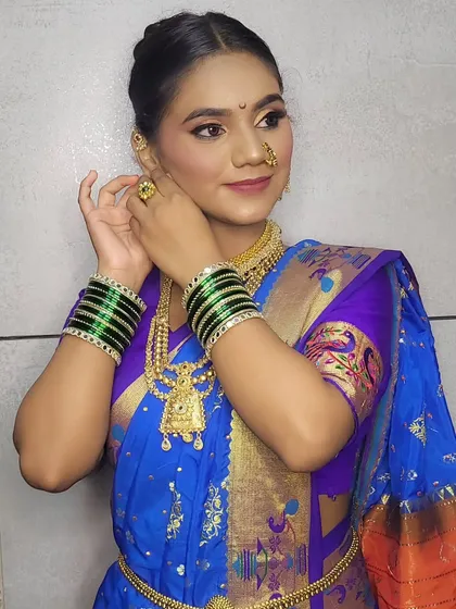 Adjusting her earrings, this shot highlights the beautiful jewelry and hairstyle for the Gudi Padwa look.