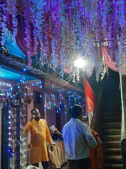 A close-up of hanging wisteria flowers used as ceiling decor, illuminated by blue lights. These small details add a lot of charm.