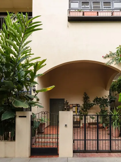The entrance to one of our most instagrammable homes. The arched entryway and lush greenery create an inviting transition from the outside world into a serene, light-filled sanctuary.