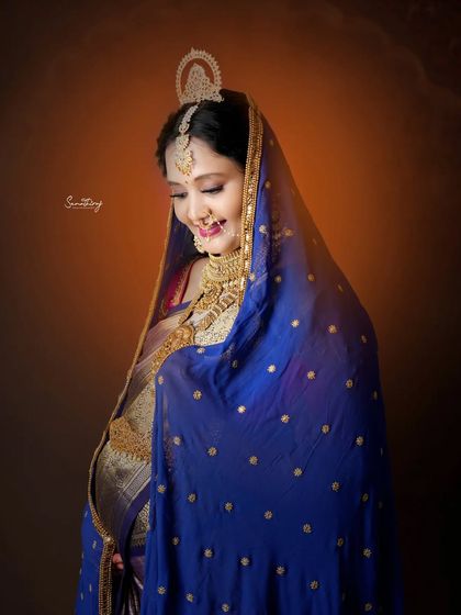 A radiant smile from a mother-to-be, draped in a beautiful blue saree with gold embroidery. This close-up portrait highlights her joy and the intricate details of her traditional attire.