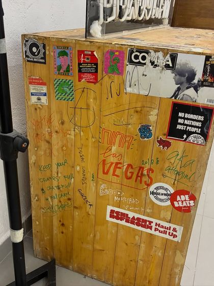 The side of the booth, showing years of tags, stickers, and memories. This object tells the story of our community.