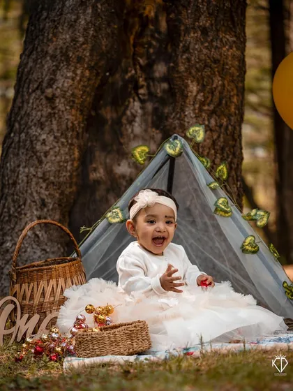 A joyful shot of the birthday girl clapping her hands inside her little tent. Her bright expression and the festive setting perfectly capture the spirit of a first birthday celebration.