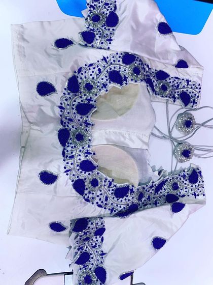 This white blouse has bold blue and silver appliqué work. The design is modern and makes a strong statement.