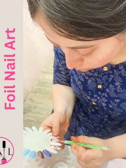 A student practices with foil nail art, learning how to transfer metallic and holographic designs onto the nail.
